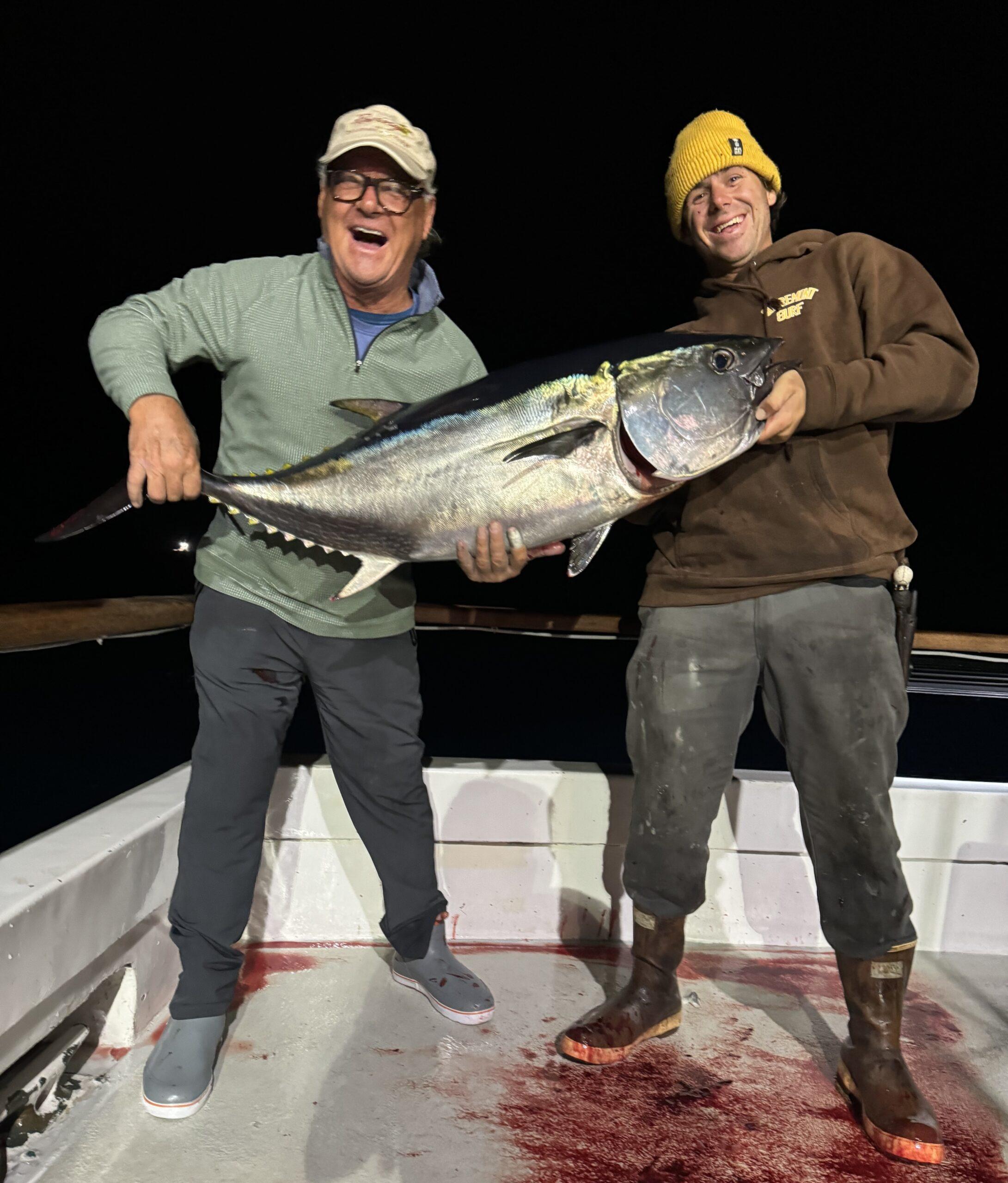 Boat crew member and angler holding a bluefin tuna.