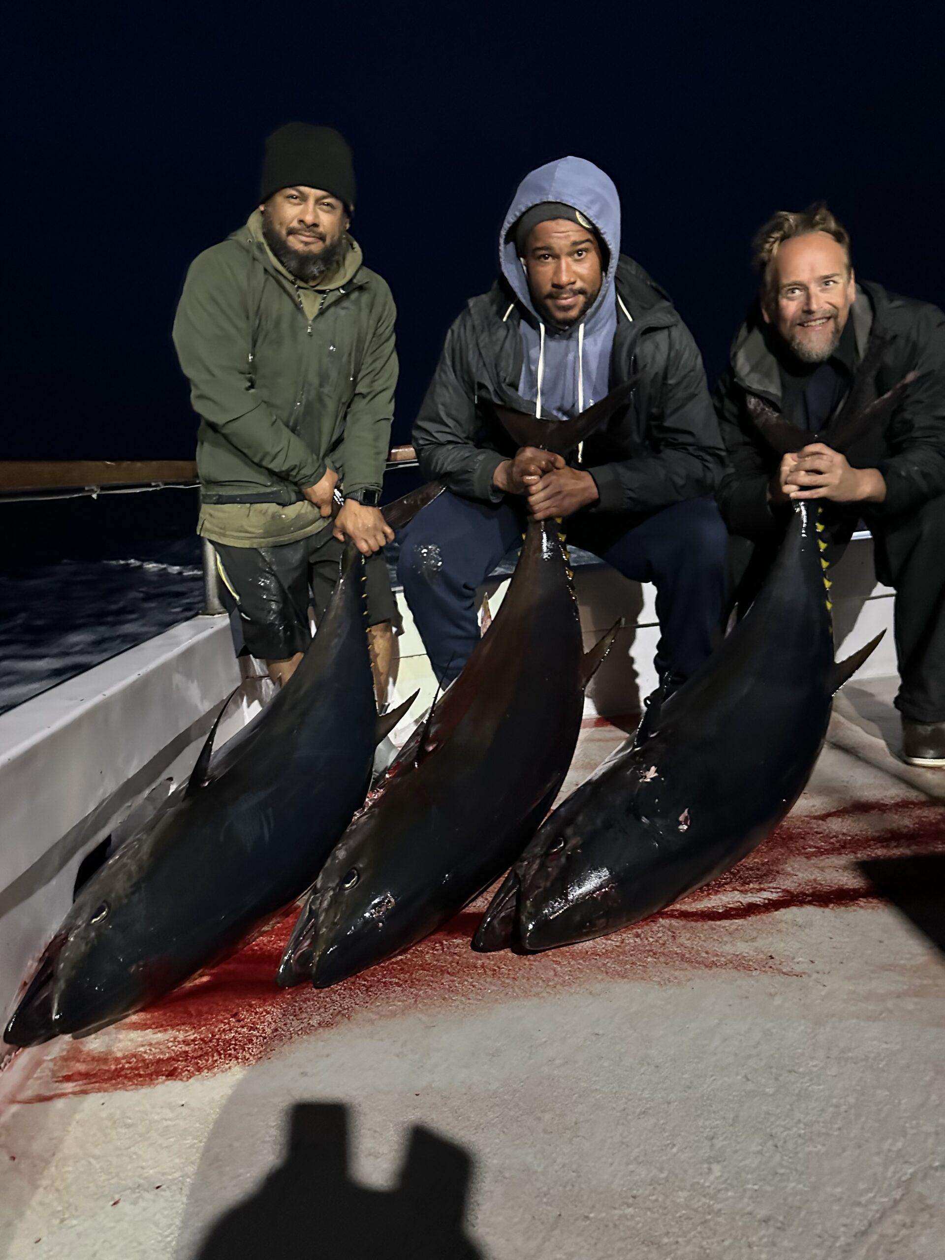 Three anglers posing with three caught bluefin tuna.